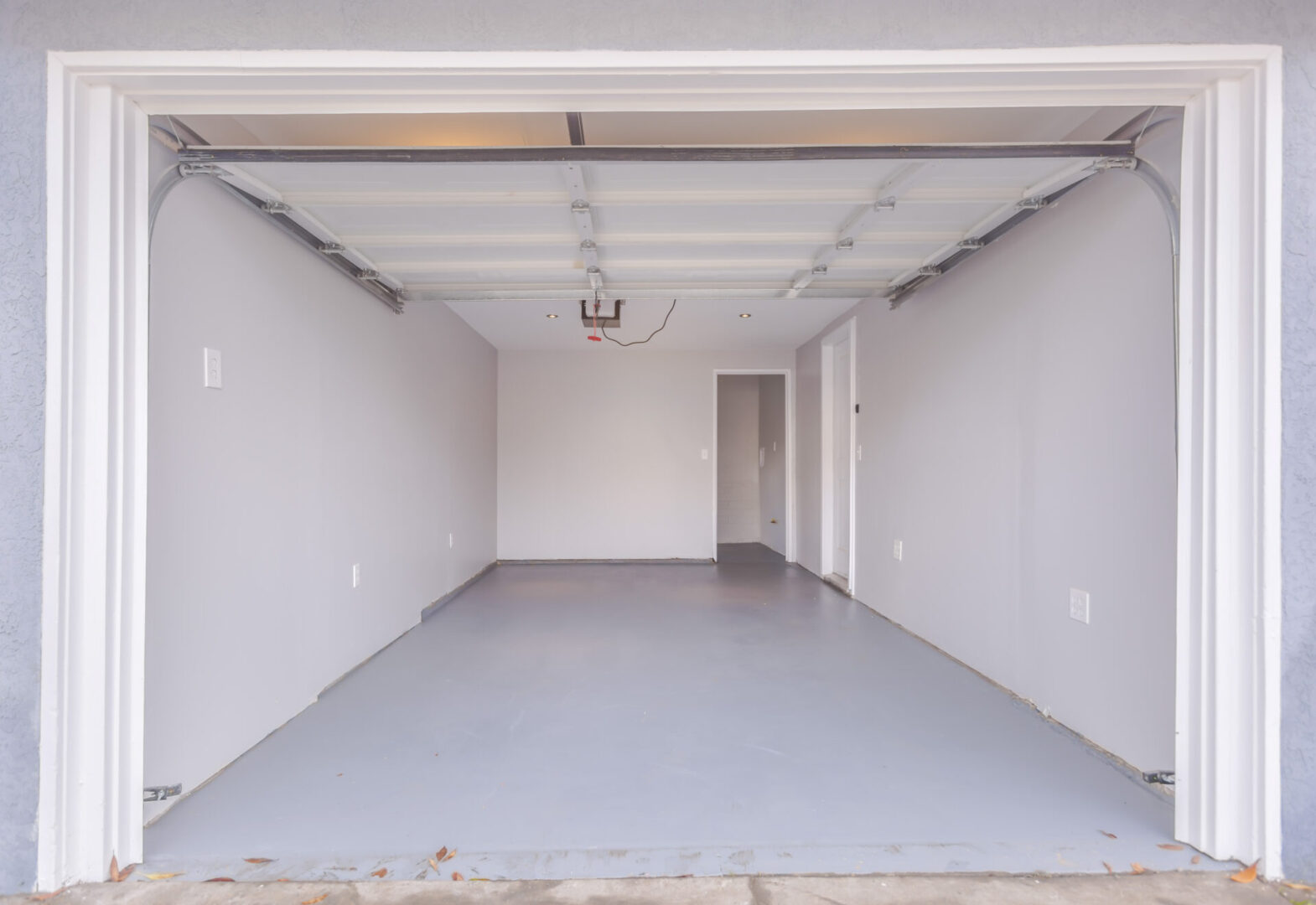 Empty, clean garage with gray floor and white walls.