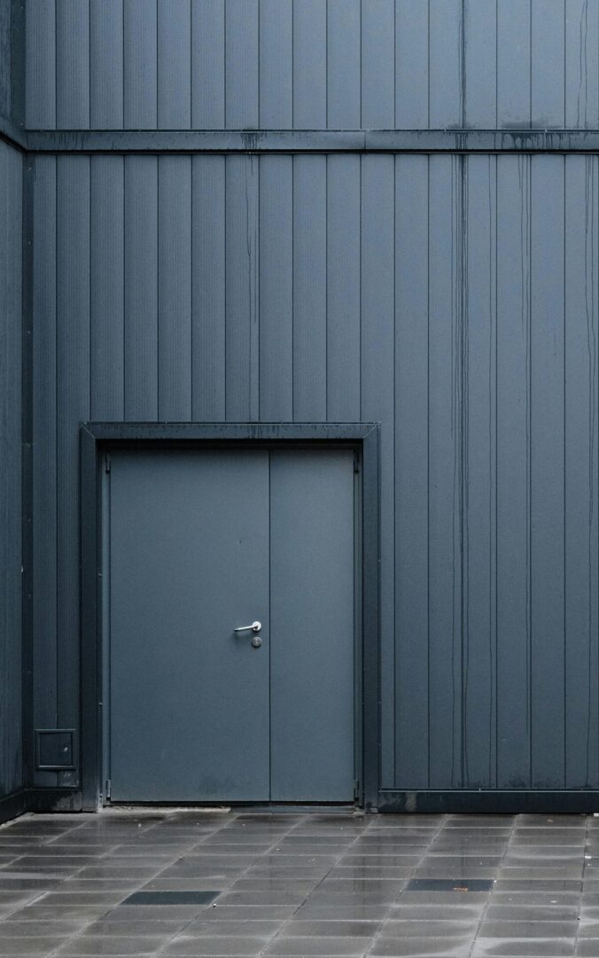 A closed gray door set in a gray paneled wall.
