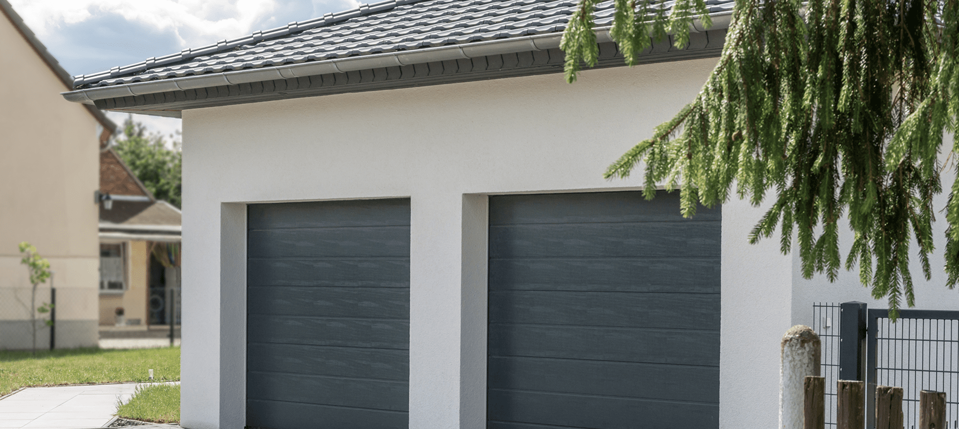 Two modern gray garage doors on a light-colored house exterior.